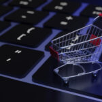 Miniatur-Einkaufswagen auf Computer-Keyboard, in bläuliches Licht getaucht