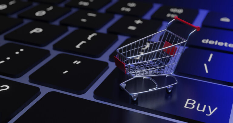 Miniatur-Einkaufswagen auf Computer-Keyboard, in bläuliches Licht getaucht