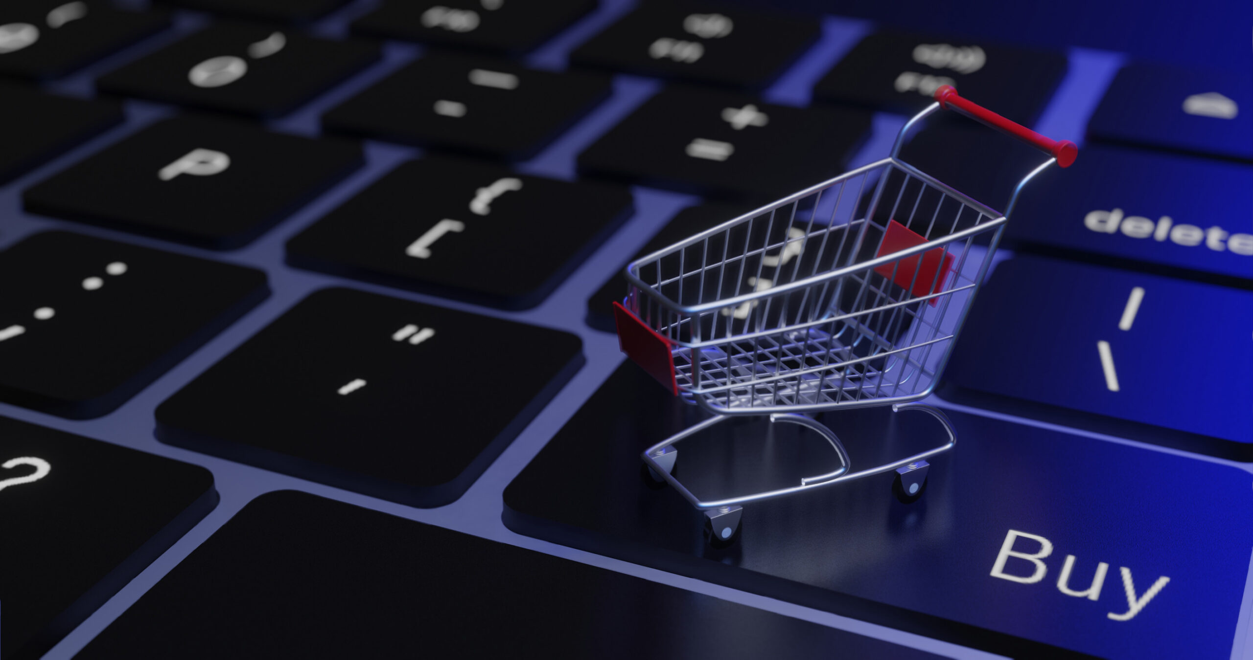 Miniatur-Einkaufswagen auf Computer-Keyboard, in bläuliches Licht getaucht