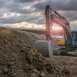 Bagger aufErdhaufen an einer Straßenbaustelle im gegenlicht.