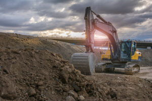 Bagger aufErdhaufen an einer Straßenbaustelle im gegenlicht.