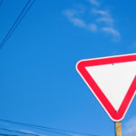 Vorfahrt-Beachten-Schild aus leichter Unzersicht gegen blauen Himmel