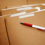 Einige braune Kartonhefter mit einem Plastikkugelschreiber.