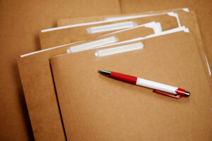 Einige braune Kartonhefter mit einem Plastikkugelschreiber.