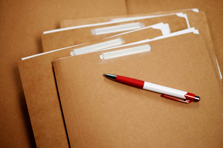 Einige braune Kartonhefter mit einem Plastikkugelschreiber.