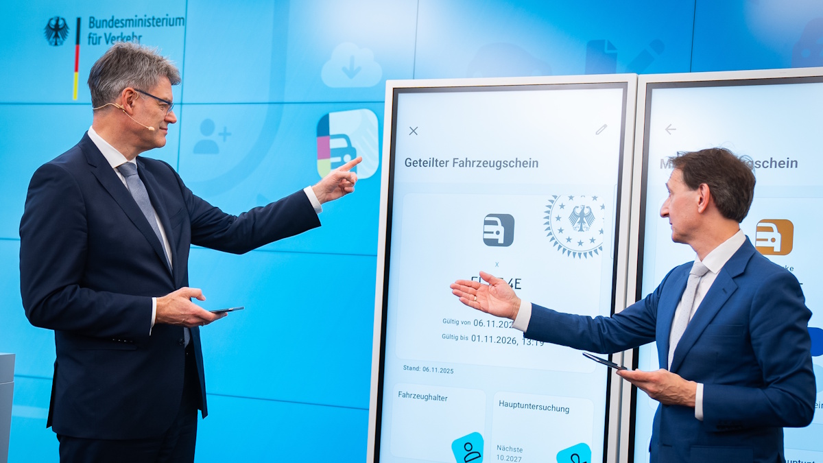 Bundesverkehrsminister Patrick Schnieder (links) präsentiert den geteilten Fahrzeugschein