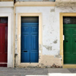 Gasse mit mehreren, bunt lackierten Eingangstüren nebeneinander