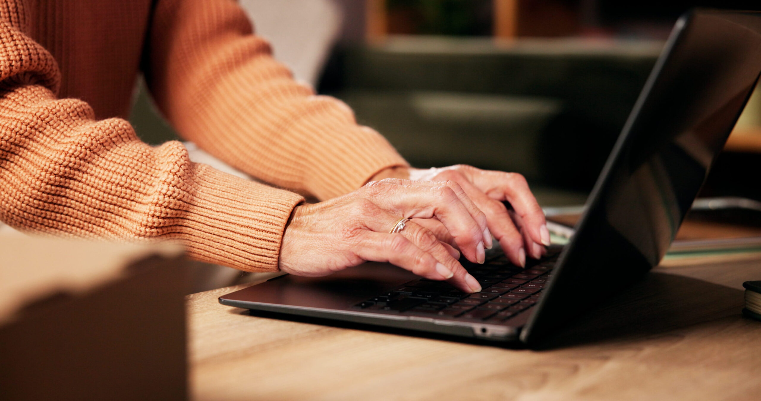 Laptop auf einem niedrigen Tisch in warmen Licht, Händet tippen darauf.