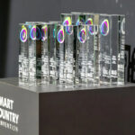 Eine Reihe von gläsernen Trophäen auf einer frauen Säule, darauf Schriftzug "Smart Country Convention"