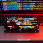 Eine Festplatte auf einer Laptoptastatur mit einer Reflexion des Programmcodes, der auf dem Bildschirm zu sehen ist.