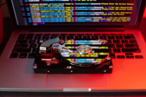 Eine Festplatte auf einer Laptoptastatur mit einer Reflexion des Programmcodes, der auf dem Bildschirm zu sehen ist.