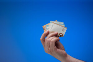 Hand mit Euronoten vor blauem Hintergrund