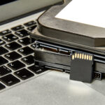 Stapel von verschiedenen IT-Speichermedien und ein aufgeklappter Laptop.