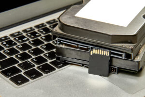 Stapel von verschiedenen IT-Speichermedien und ein aufgeklappter Laptop.