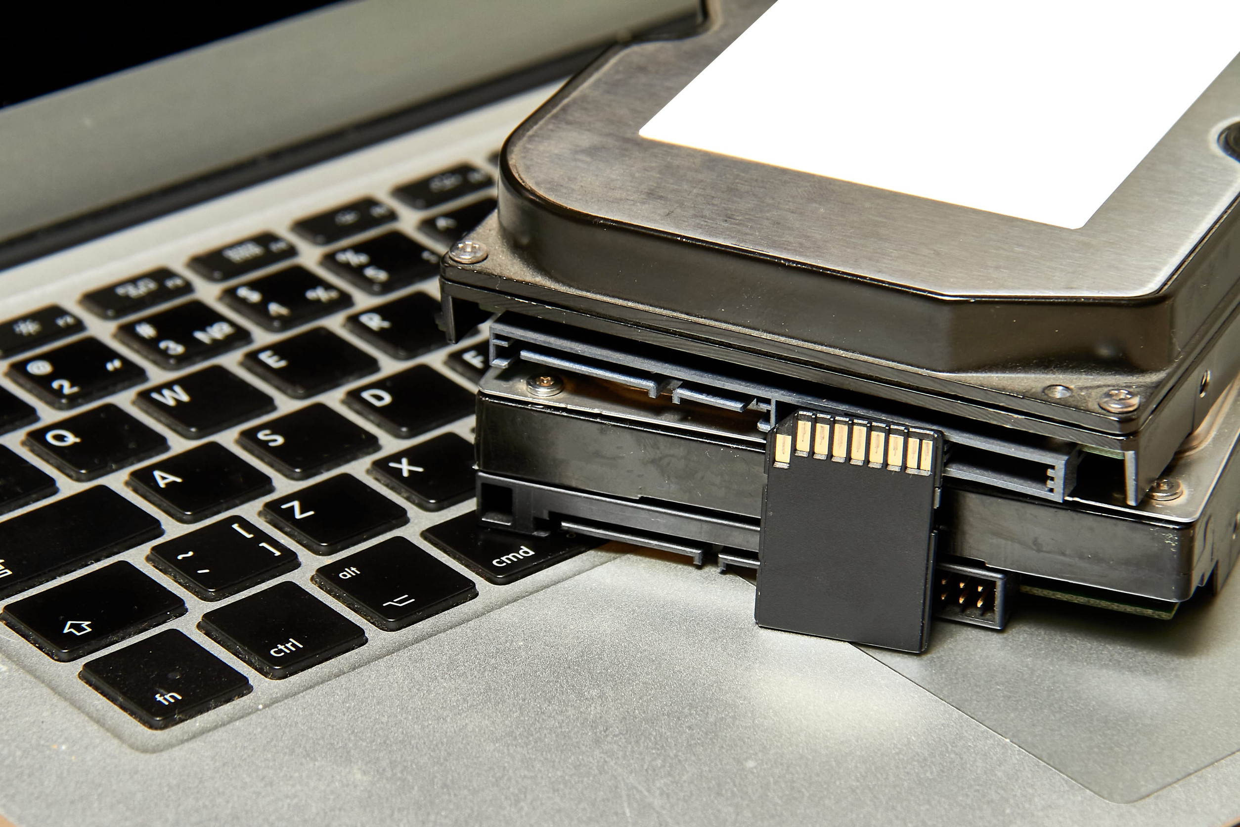 Stapel von verschiedenen IT-Speichermedien und ein aufgeklappter Laptop.