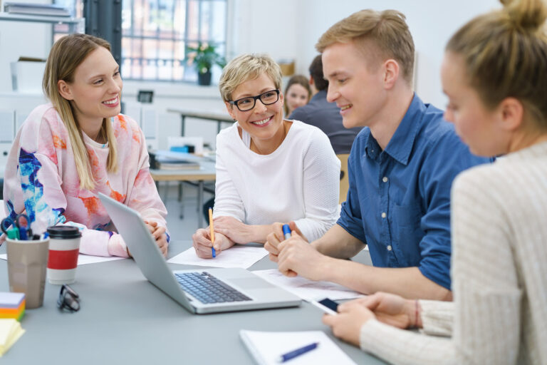 Motiviertes junges Arbveitsteam sitzt an einem Tisch