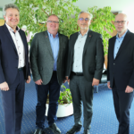 Vier_Männer_vor_einer Pflanze_partnerschaft_iBYKUS-Inwerken