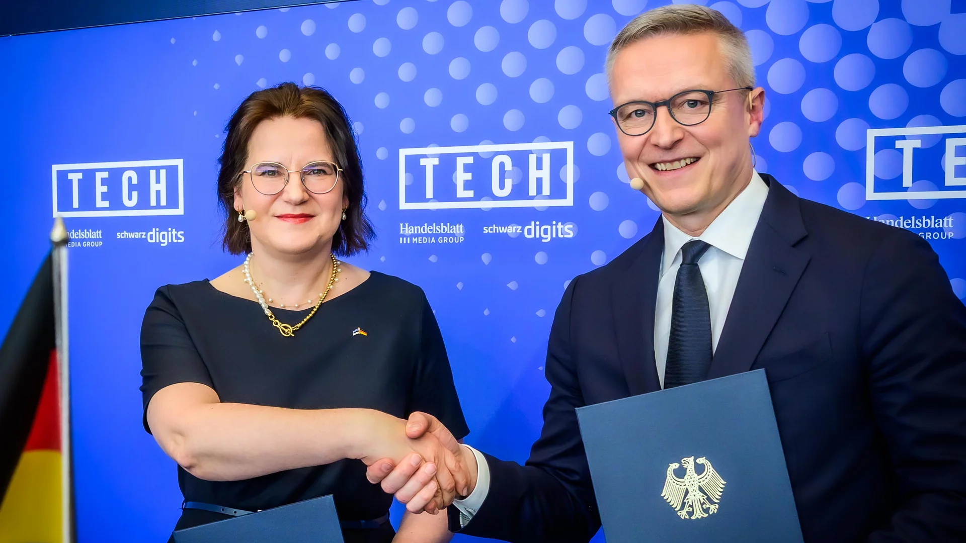 Handshake-Pose von Pakoste und Wildberger vor blauem Hintergrund