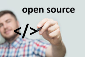 Montage: Junger Mann im Karohemd schreibt mit einem Marker auf eine imaginäre Glaswand die Worte "open source"