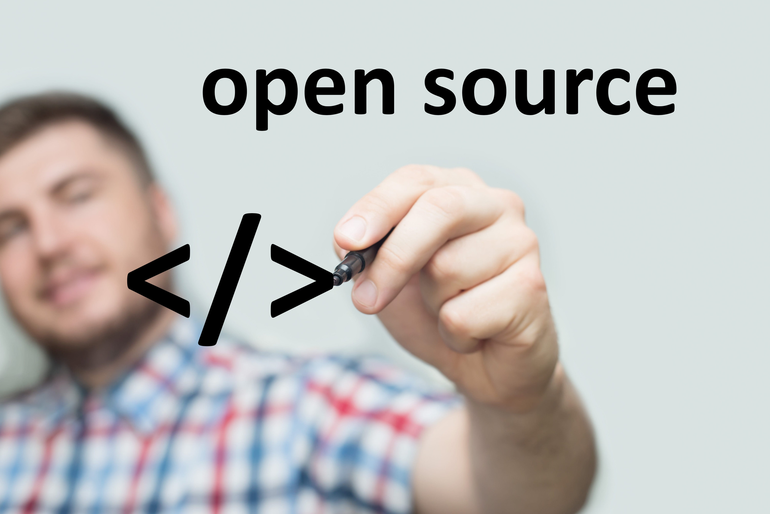 Montage: Junger Mann im Karohemd schreibt mit einem Marker auf eine imaginäre Glaswand die Worte "open source"