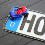 Deutsches Nummernschild plus Spielzeugauto auf einem Holztisch