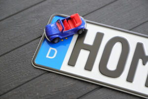 Deutsches Nummernschild plus Spielzeugauto auf einem Holztisch